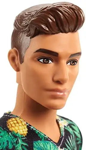Bambola maschile dai capelli castani, con dettagli facciali accurati e una camicia a motivo tropicale.