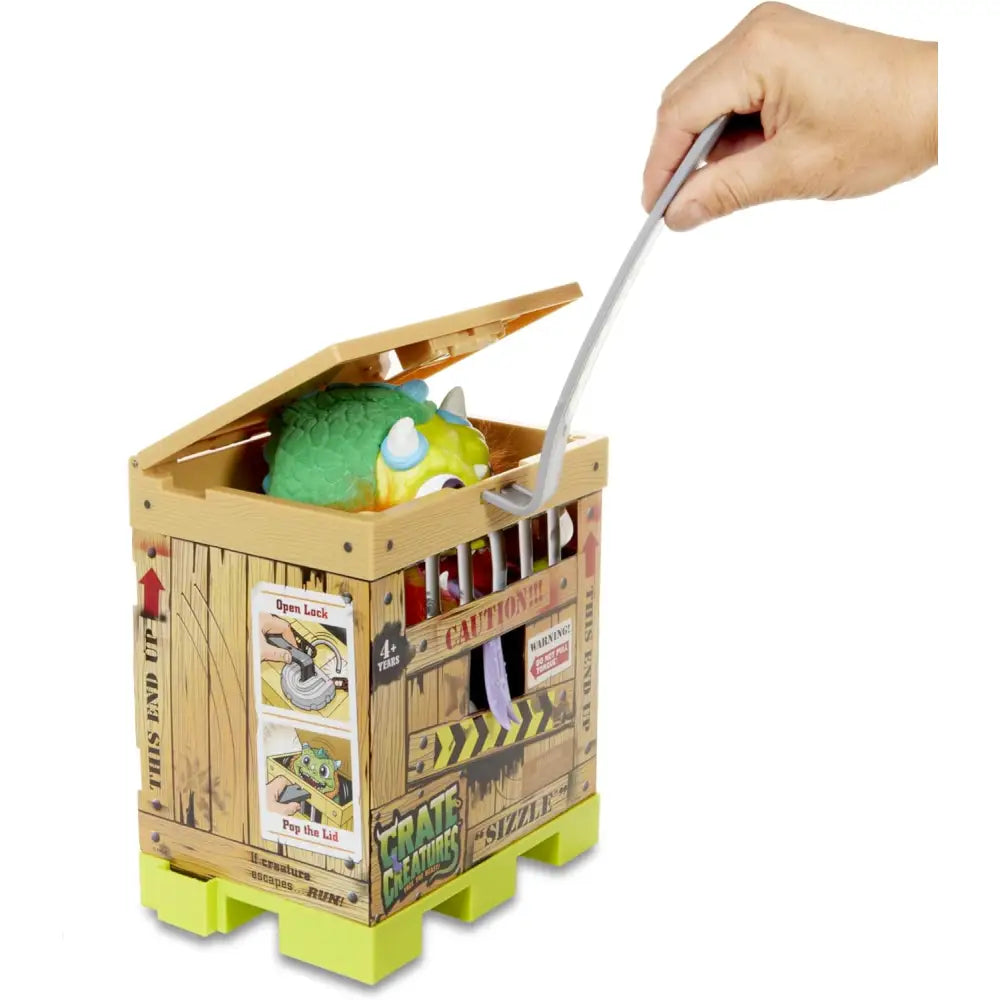 Un drago interattivo verde e giallo in plastica crate creatures sizzle seduto in una scatola di legno crate creatures