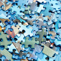 Una pila di pezzi frozen jigsaw puzzle 1000 pezzi con disegni intricati blu e verdi colorati