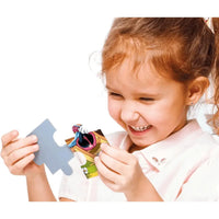 Un bambino tiene un pezzo grigio del puzzle maxi supercolor disney mickey sopra un puzzle colorato a tema cartone animato